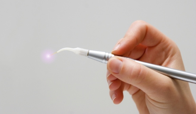 Hand holding a metal pen like dental laser