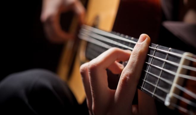 Close up of person placing acoustic guitar