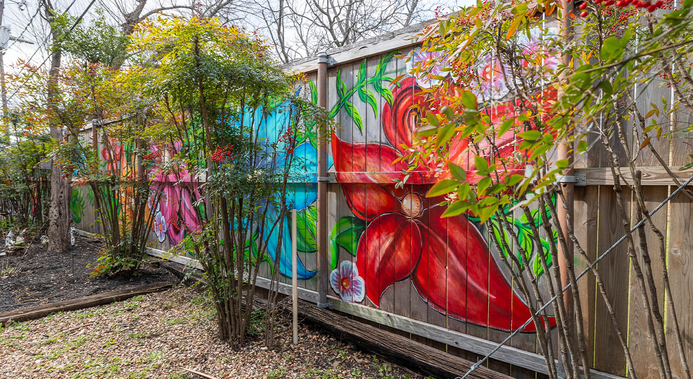 Wooden fence with several different colored flowers painted onto it