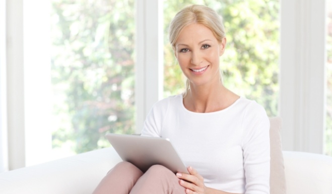 Smiling woman sitting on couch with a tablet