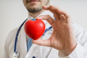 Doctor holding a small red heart toy