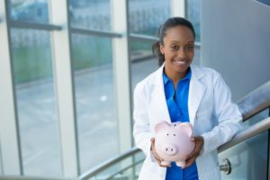 dentist in San Marcos holding a pink piggy bank