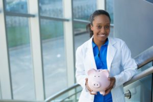 dentist in San Marcos holding a pink piggy bank 