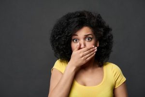 Concerned woman with hand over mouth needs to see San Marcos Dentist