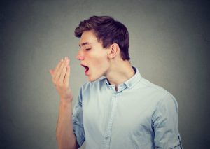 Young man checking his breath with hand