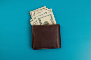 Brown wallet with money on bright blue background